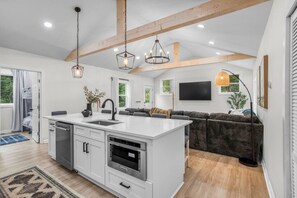 A modern kitchen with a central island, built-in appliances, and pendant lighting.