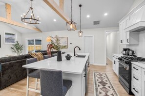 A modern kitchen with white cabinets, a central island, and a built-in oven.