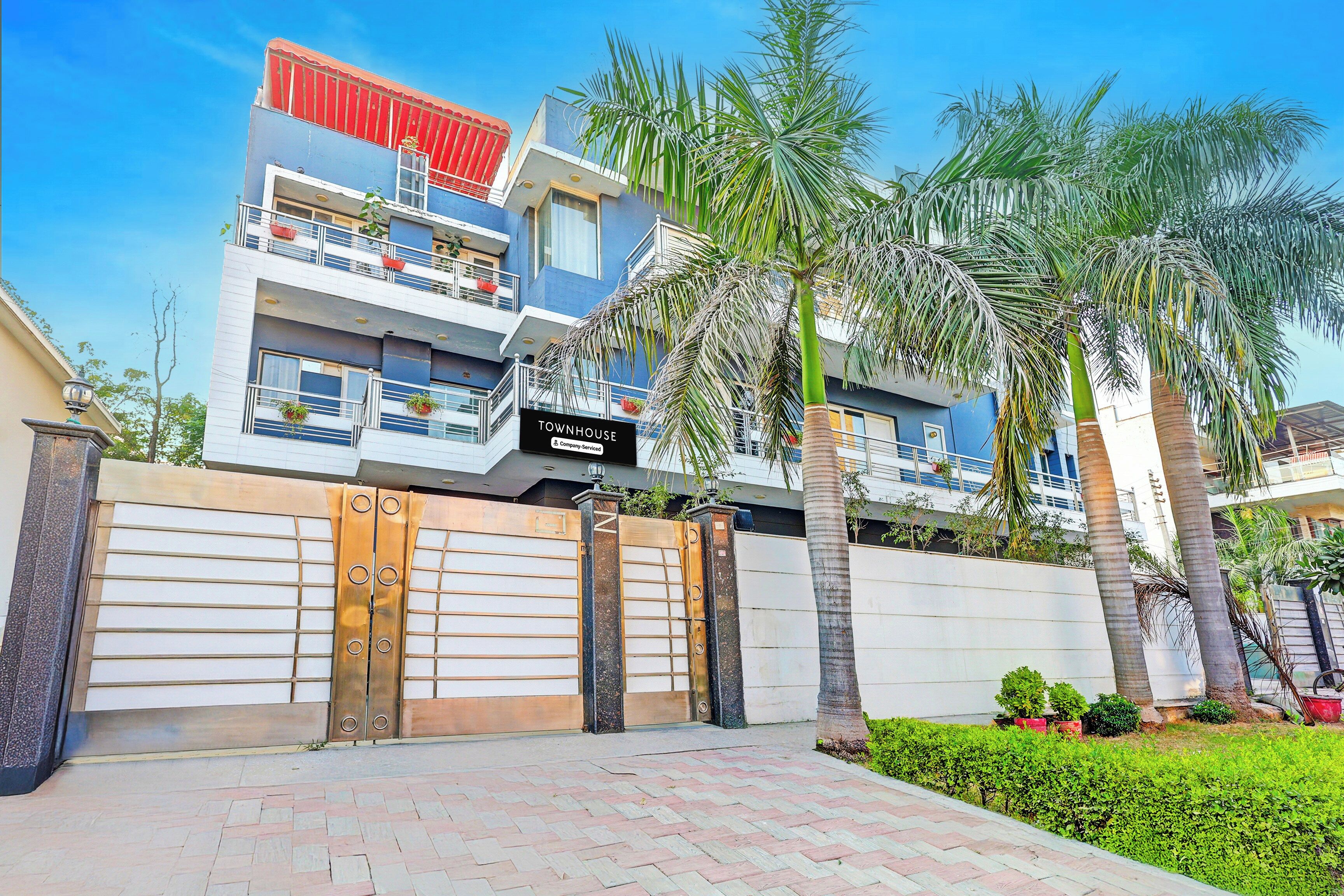 A multi-story residential building with a gated entrance, balconies, and a sign indicating it is a townhouse.