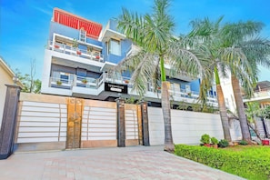 A multi-story residential building with a gated entrance, balconies, and a sign indicating it is a townhouse.