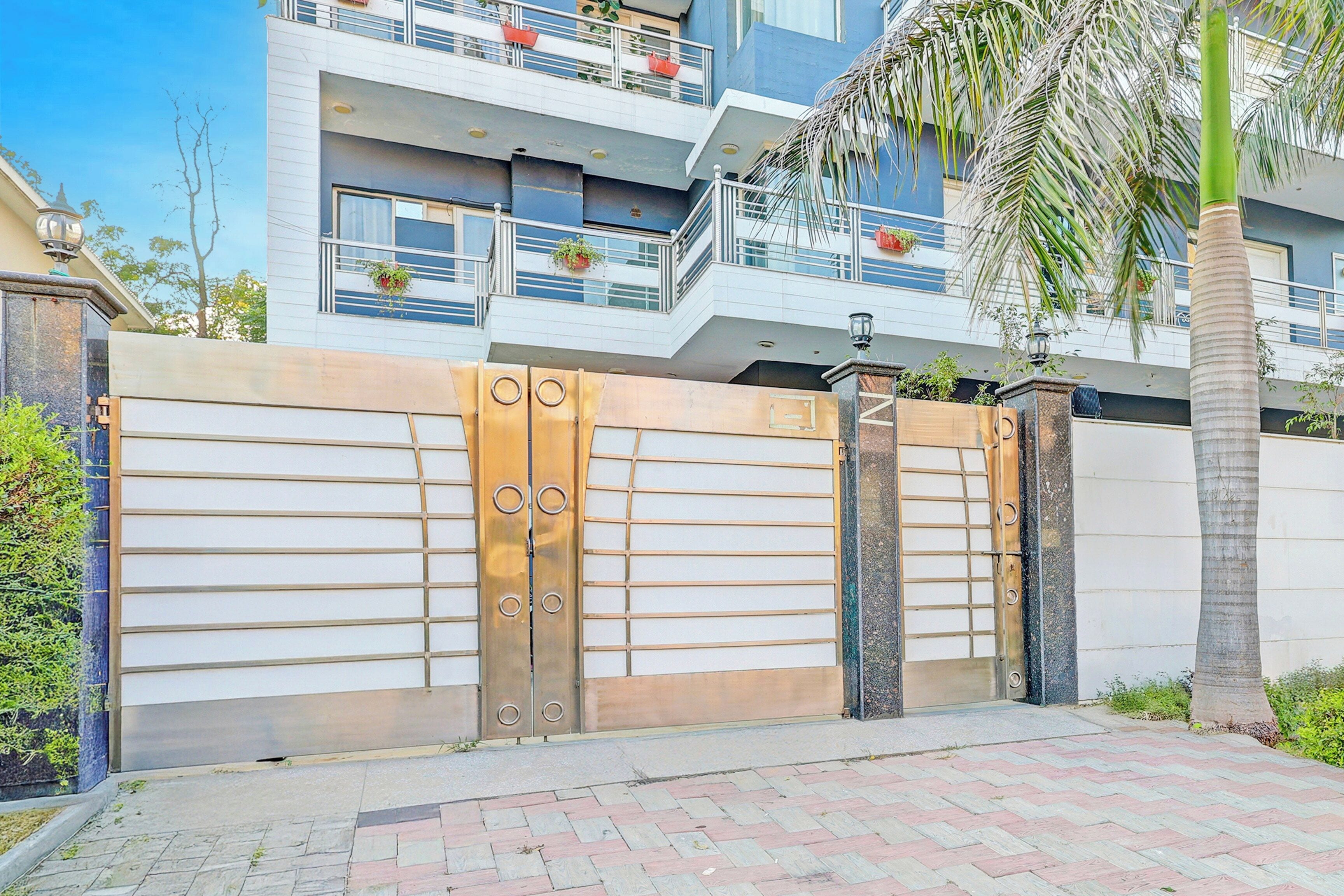 A gated entrance with a metal gate and a palm tree in the foreground.