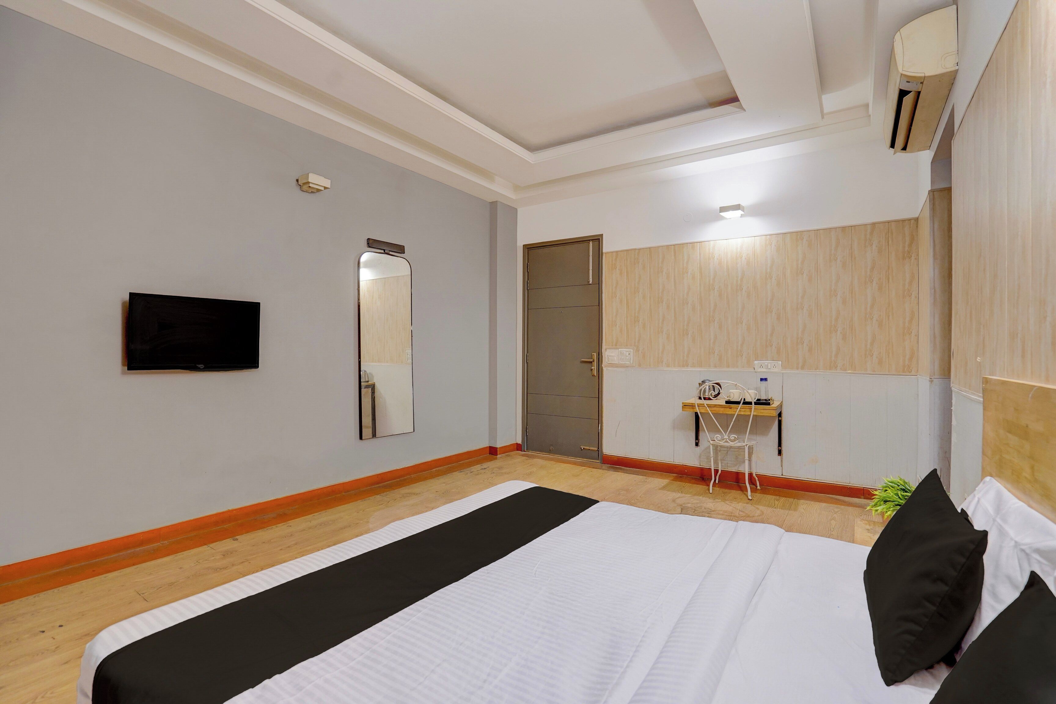 Una habitación de hotel con una cama, un escritorio, una silla, un espejo y un televisor.