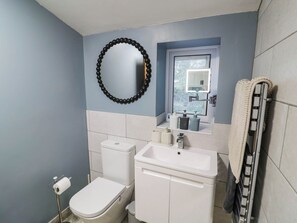 A bathroom with a toilet, sink, and a towel rack. - Lilac Cottage (Rugby)