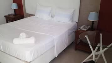 Una habitación de hotel con una cama grande, dos mesitas de noche, una silla y un teléfono.