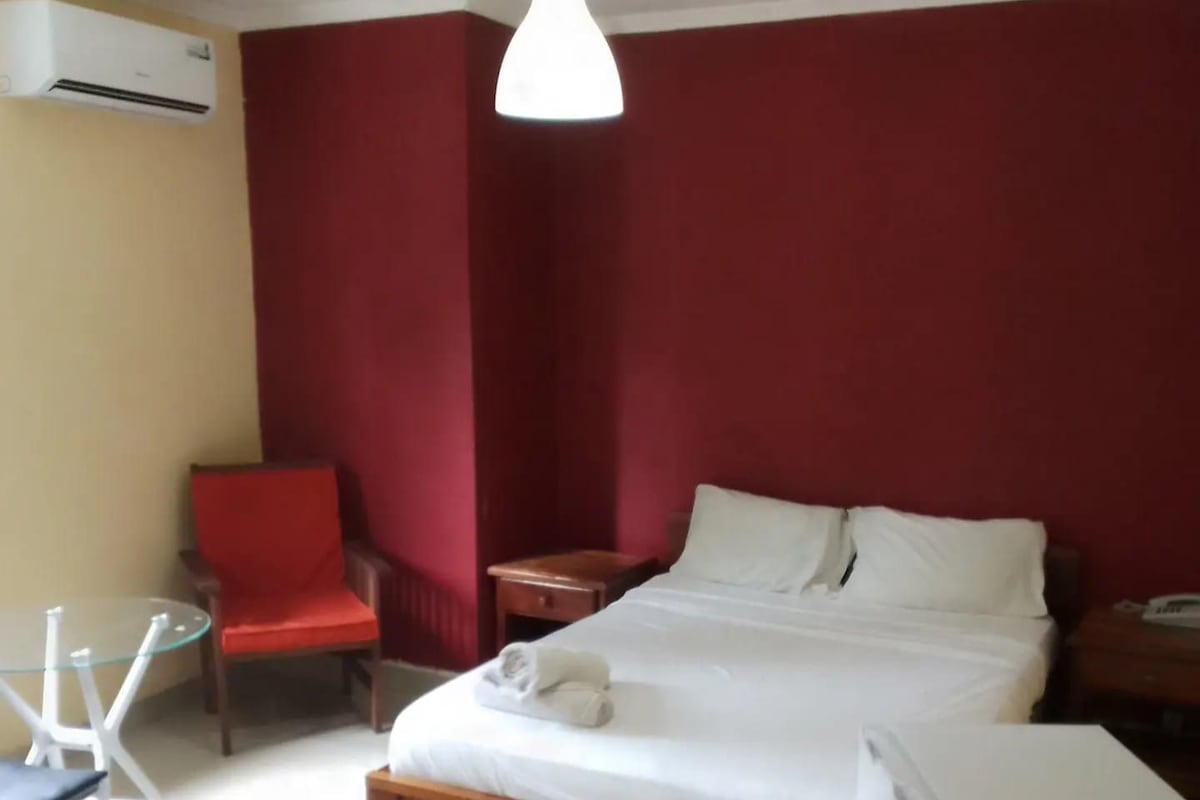 A hotel room with a bed, a chair, a table, and a desk.
