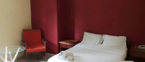 A hotel room with a bed, a chair, a table, and a desk.