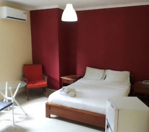 A hotel room with a bed, a chair, a table, and a desk. - Angola Stay Connect (Luanda)