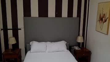 Habitación de hotel con una cama grande, dos mesitas de noche, un cabecero y una lámpara de pared.