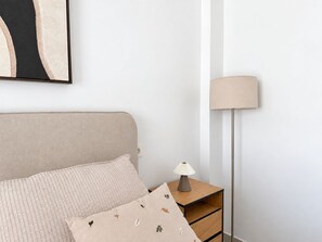 A bedroom with a bed, a bedside table with a lamp, and a wall-mounted artwork. - La Casa Eliana 3-bedroom Apartment (AN)