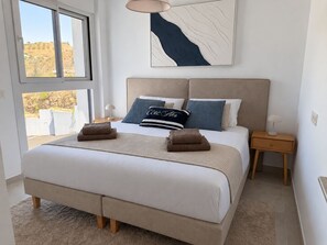 A bedroom with a large bed, a headboard, bedside tables, a window, and a painting on the wall. - La Casa Eliana 3-bedroom Apartment (AN)