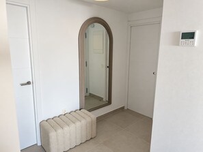 A hallway with a bench, a mirror, and a thermostat on the wall. - La Casa Eliana 3-bedroom Apartment (AN)