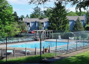 A swimming pool with a fenced deck, lounge chairs, and a building in the background. - Luxurious, light-filled 2 bedroom condo in Bloomington IU Football Fans (Bloomington)