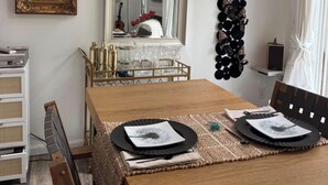 Zona pranzo con tavolo in legno, sedie, uno specchio e decorazioni a parete tra cui un quadro incorniciato e un motivo circolare nero.