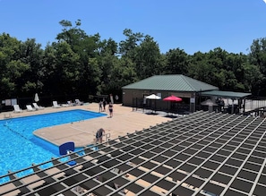 A swimming pool area with a covered pavilion, lounge chairs, and a fenced deck.