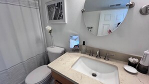 Un bagno con il water, un lavandino, uno specchio e un quadro appeso al muro.