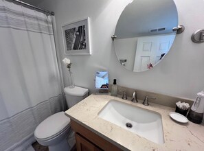 A bathroom with a toilet, sink, mirror, and a framed picture on the wall. - Luxurious, light-filled 2 bedroom condo in Bloomington IU Football Fans (Bloomington)