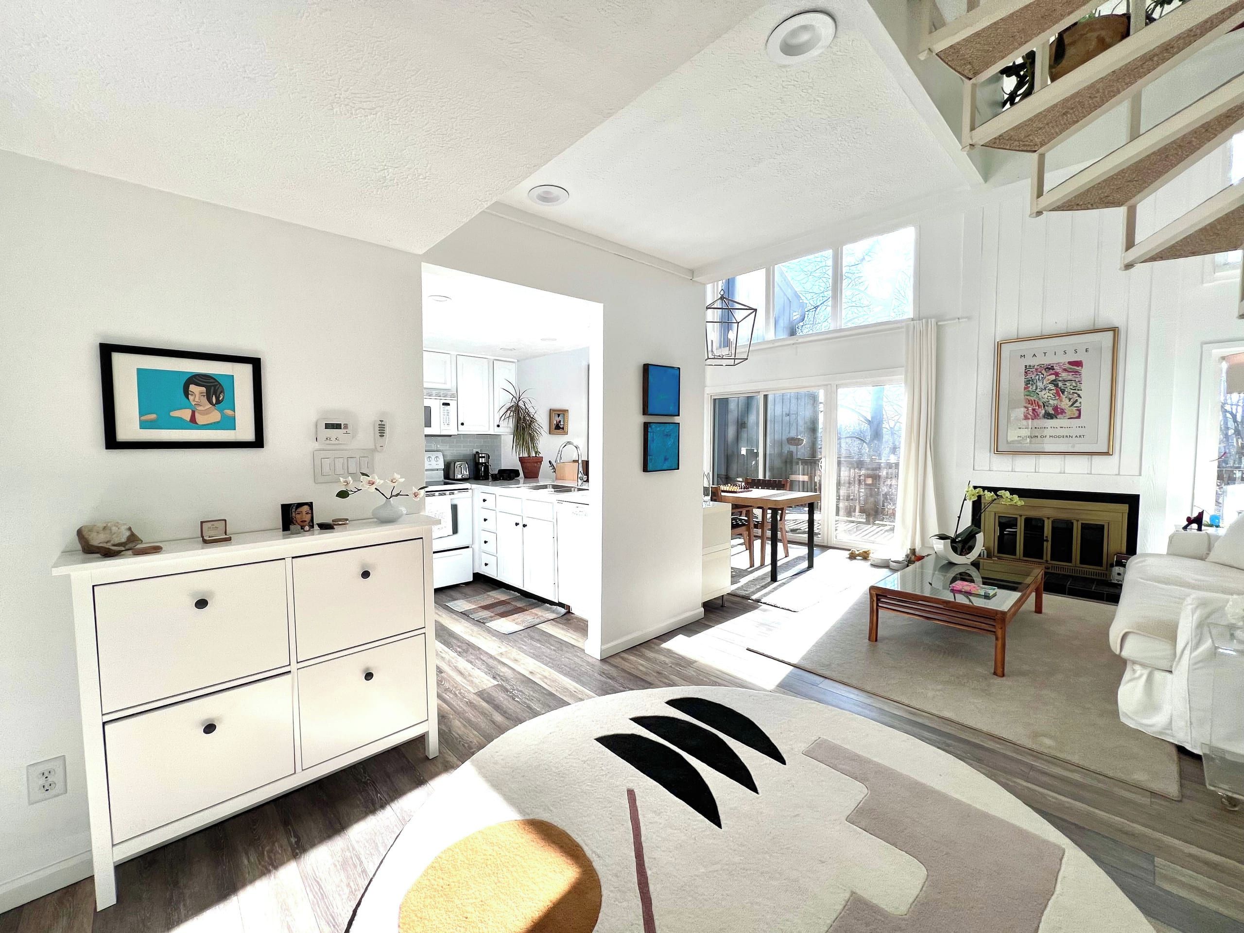 A spacious living room with a fireplace, a dining area, and a kitchen with white cabinetry.