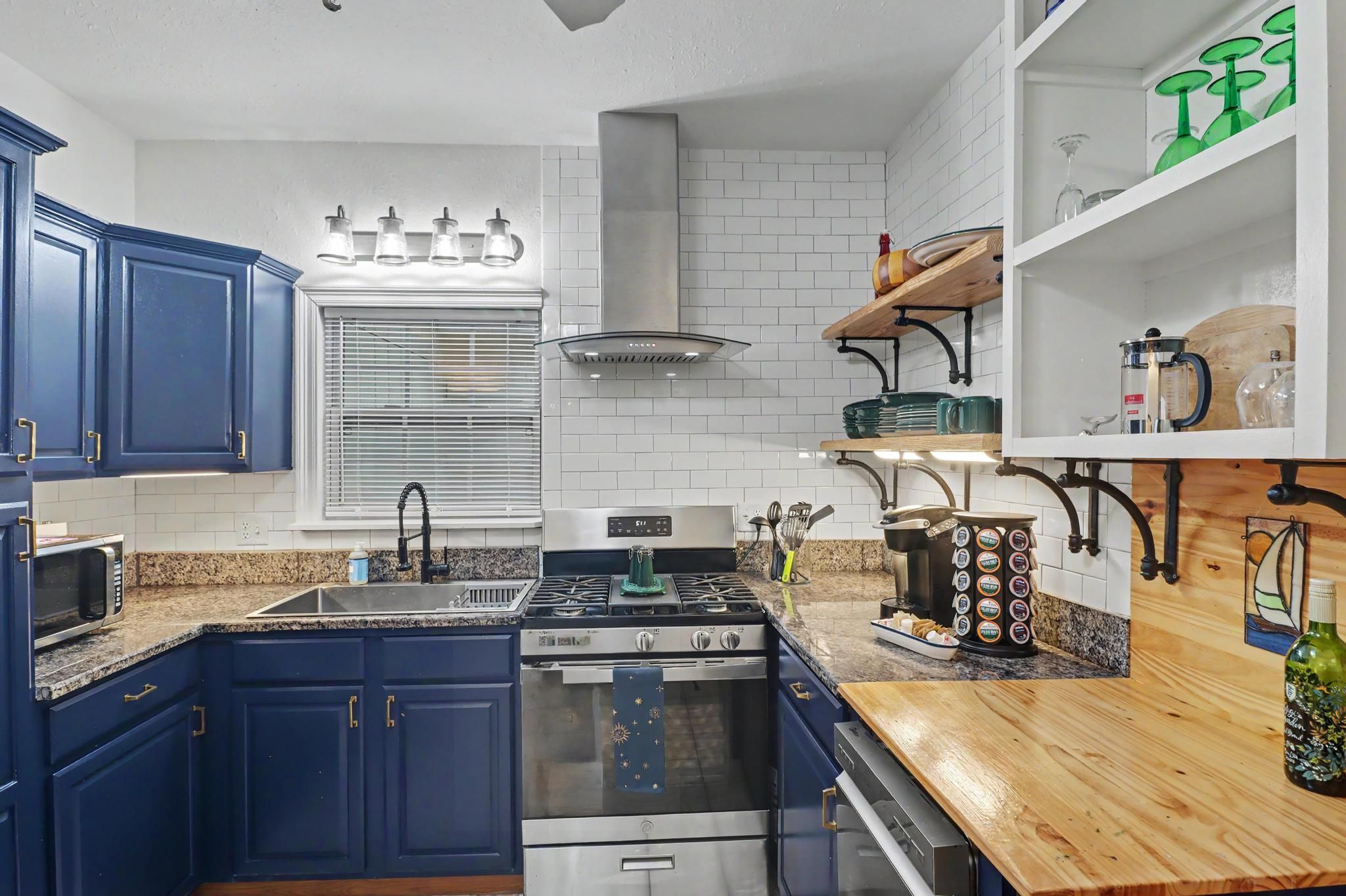 Une cuisine avec des armoires bleues, une cuisinière en acier inoxydable, un four à micro-ondes et un plan de travail en bois.