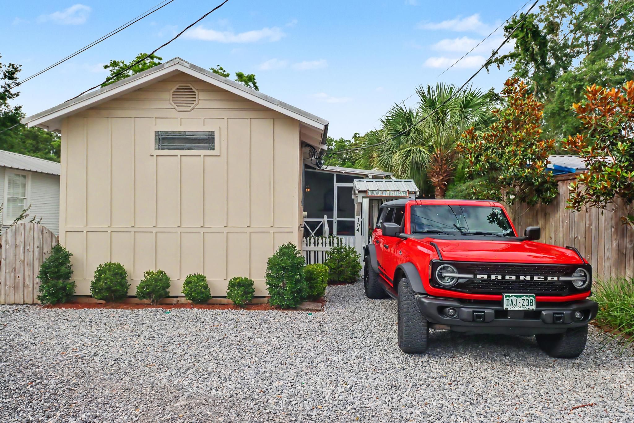 A red truck parked in front of a beige building with a gravel driveway.