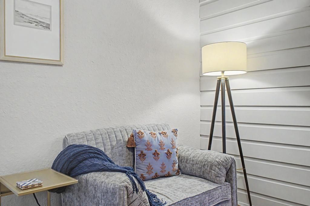 A room with a sofa, a small table, a lamp, and a framed picture on the wall.