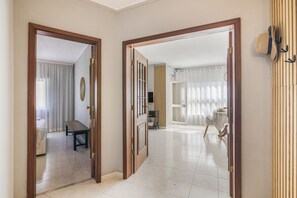 A hallway with a bench, a table, and a dining area with chairs and a table. - Caprichoso Beachfront Apartment with Shared Pool, Balcony, and Air Conditioning (Armação de Pêra)