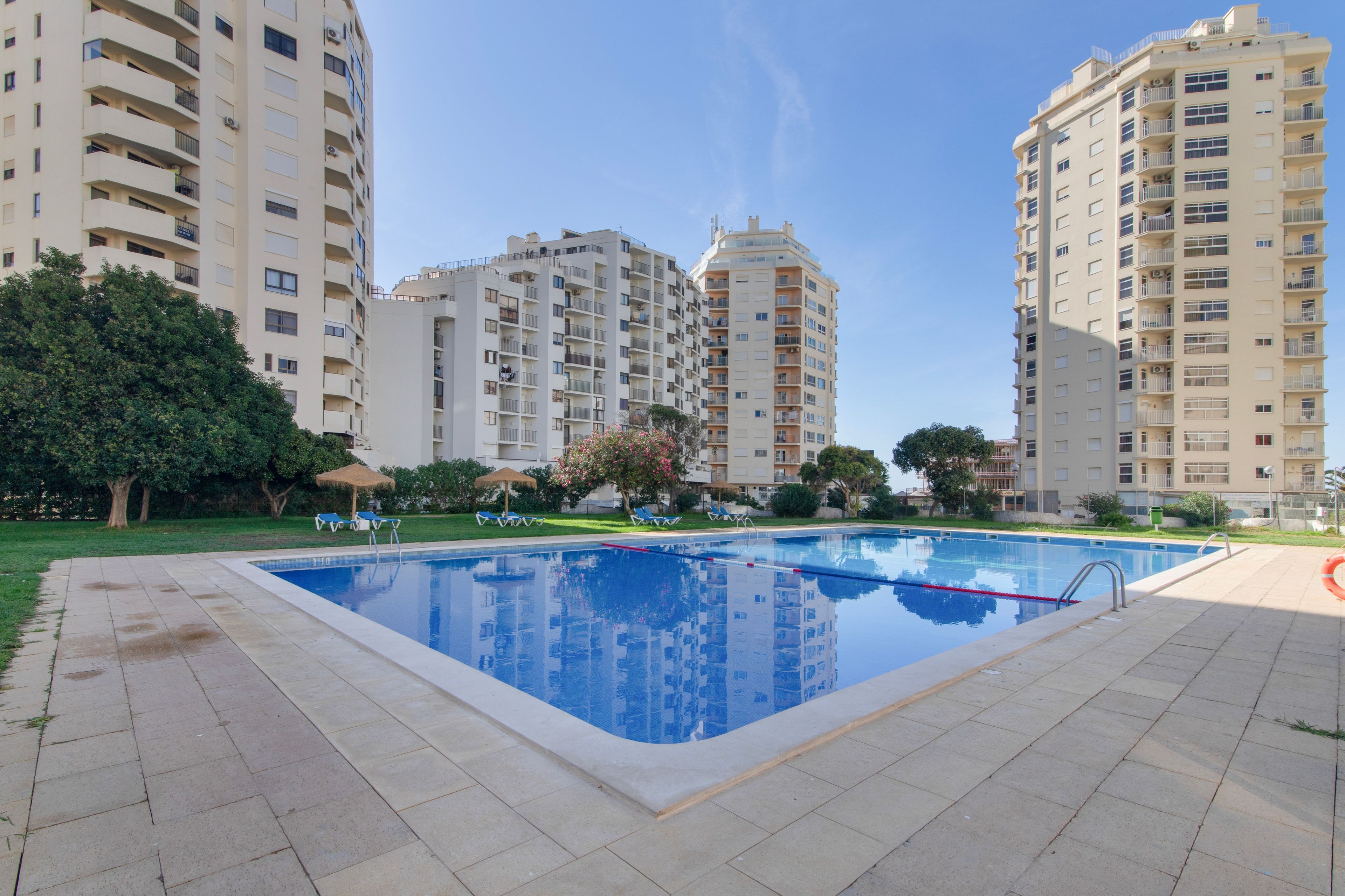 A swimming pool surrounded by apartment buildings, with a clear sky above.