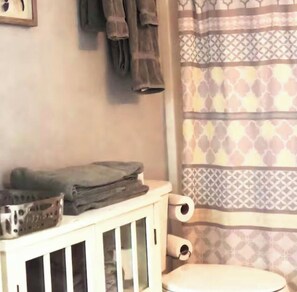 Une salle de bain avec des toilettes, un rouleau de papier toilette, un lavabo et des serviettes accrochées au mur.