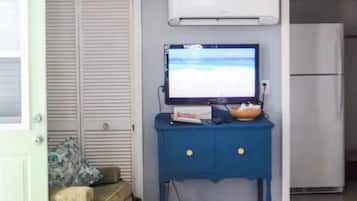 Een kamer met een gesloten deur, een blauwe kast met een televisie en een witte koelkast.
