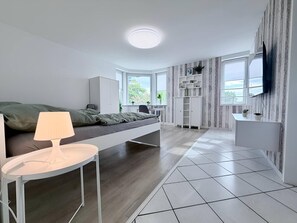 A modern bedroom with a bed, bedside table, and a desk area. - City View II Vacation Rental – Terrace & Downtown (Nordhorn)