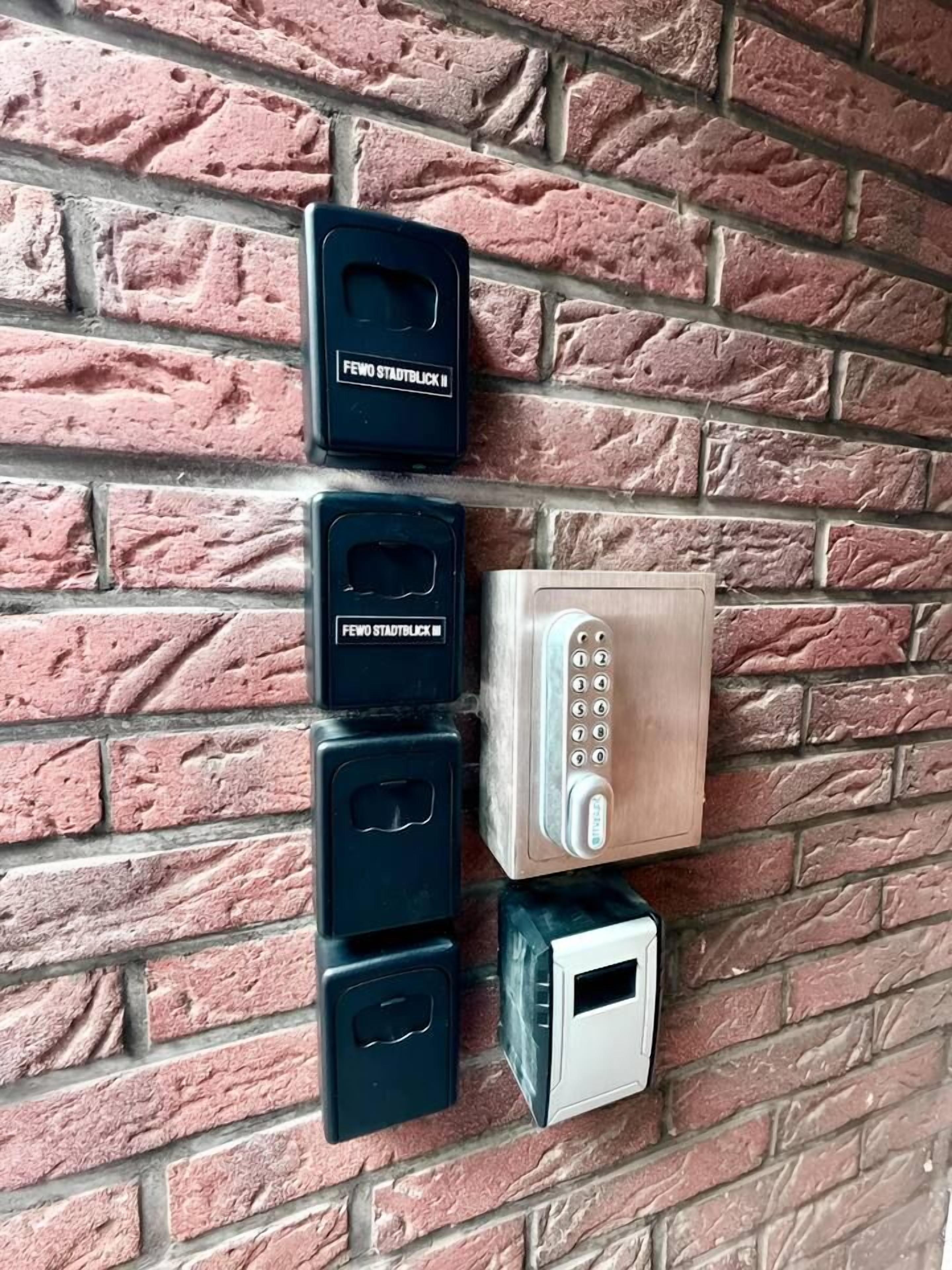 A wall-mounted security keypad and four keypads against a brick wall.
