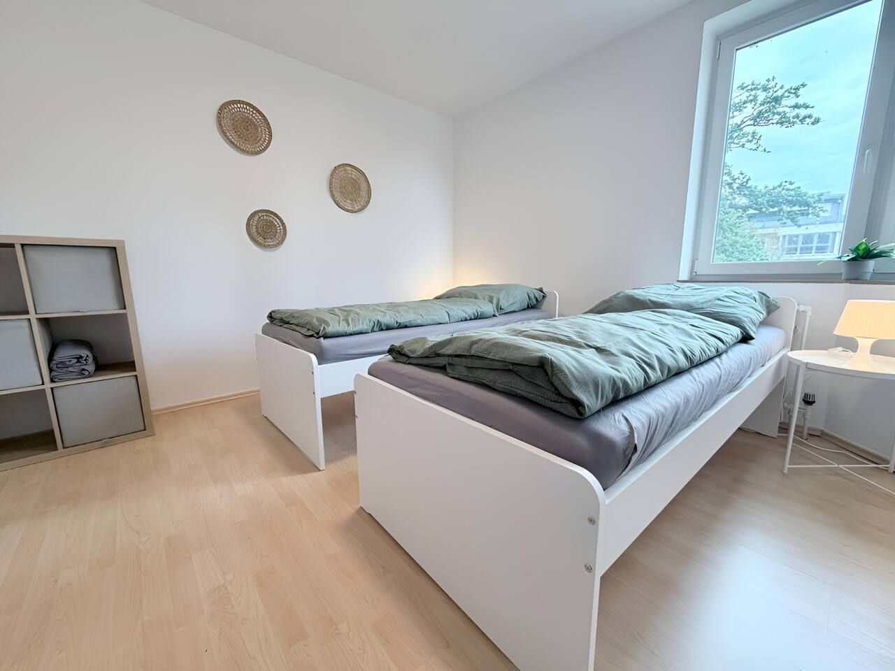 Una habitación con dos camas, un escritorio pequeño y una ventana.