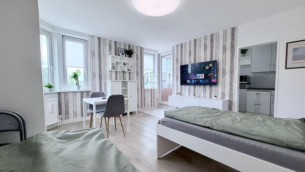 Ein modernes Schlafzimmer mit Bett, Schreibtisch und Fernseher.