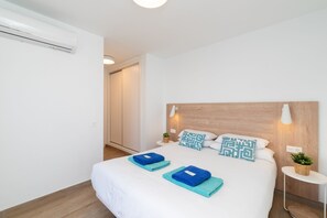A hotel room with a bed, a bedside table, a wall-mounted light, and a wooden headboard. - Ereza Villas La Granja 2 (Yaiza)