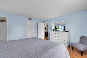 A bedroom with a bed, a dresser, a chair, and a television. - Sea Club #43 - The Shore Thing (Indian Shores)