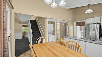 Una cocina moderna con una mesa de comedor de madera, armarios blancos y un refrigerador de acero inoxidable.