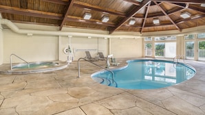 An indoor swimming pool with a stone floor, wooden ceiling beams, and a view of greenery outside. - Sunrise Ridge Resort  (Pigeon Forge)