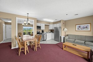 Un espacio habitable pequeño con zona de comedor, kitchenette y sofá.