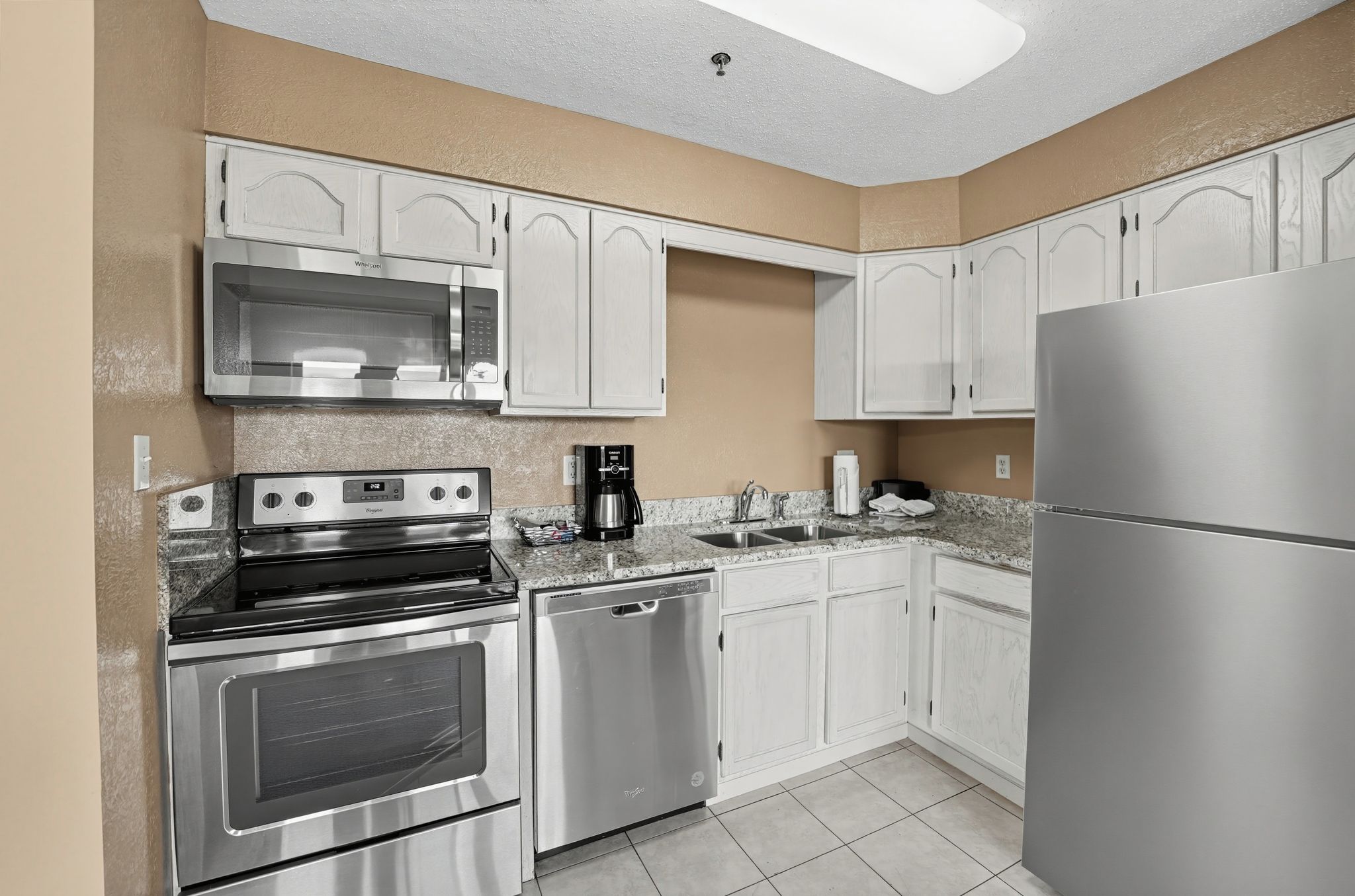 A kitchen with white cabinets, stainless steel appliances including a microwave, stove, dishwasher, and refrigerator.