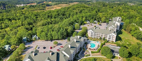A large hotel complex with multiple buildings, a parking lot, and a swimming pool.