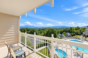 A balcony with a view of a mountain range, a swimming pool, and outdoor furniture. - Sunrise Ridge Resort  (Pigeon Forge)