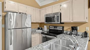 Una cocina moderna con electrodomésticos de acero inoxidable, encimeras de granito y armarios color beige.