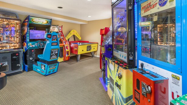 A row of arcade games in a room with carpeted flooring and beige walls. - Sunrise Ridge Resort  (Pigeon Forge)