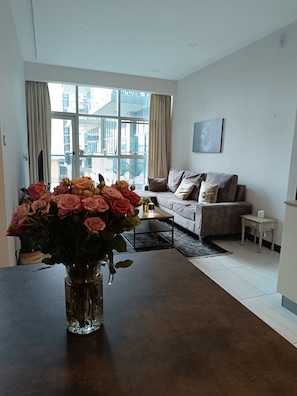 Ein modernes Wohnzimmer mit großem Fenster, einer Couch, einem Couchtisch und einer Blumenvase.