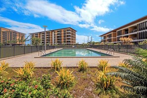 A modern outdoor swimming pool surrounded by a fence, with a clear sky above. - The Salty Lagoon A Vibrant Retreat by the Water (Darwin)
