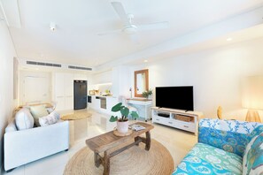 Ein modernes Wohnzimmer mit Sofa, Couchtisch, Fernseher und Deckenventilator.