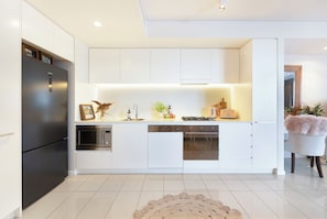 Une cuisine moderne avec des meubles blancs, des appareils électroménagers en acier inoxydable et un îlot central.