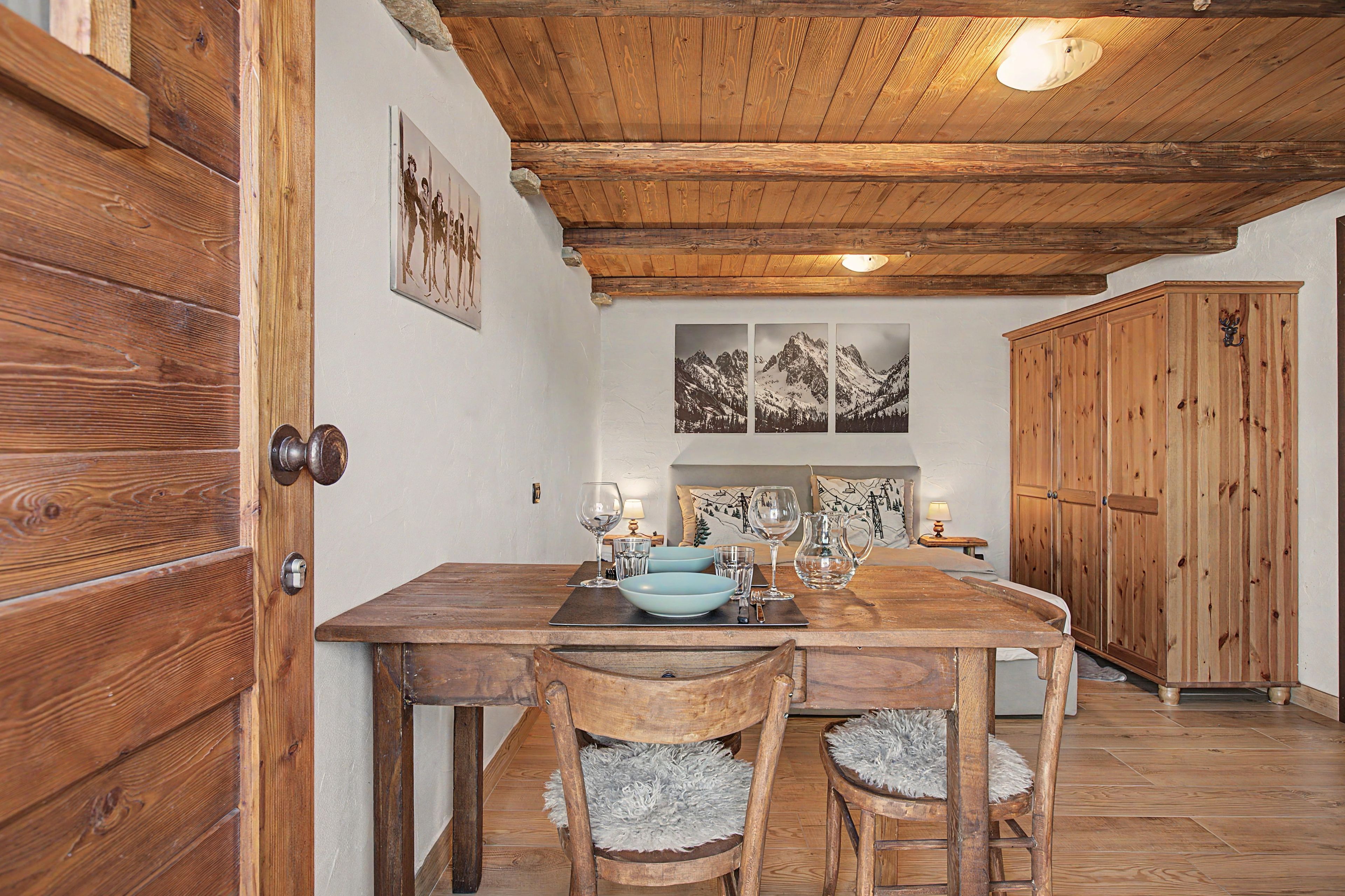 Ein Holztisch mit Stühlen, eine Holzkommode und Bilder an der Wand.
