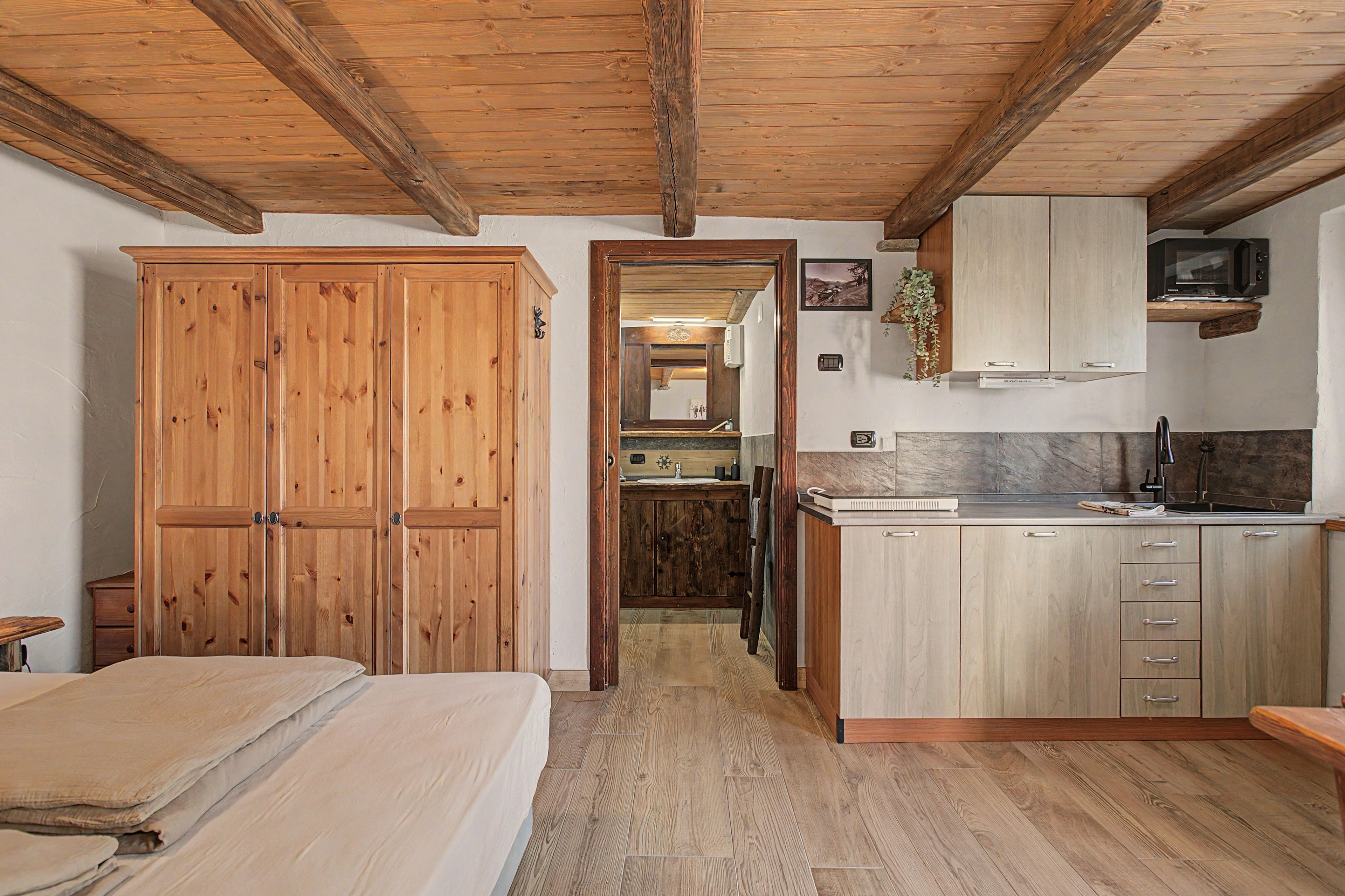 A compact bedroom with a wooden wardrobe, a bed, and a small bedside table.