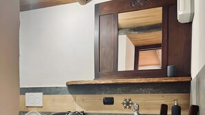 A bathroom with a wooden vanity, a sink, and a mirror.