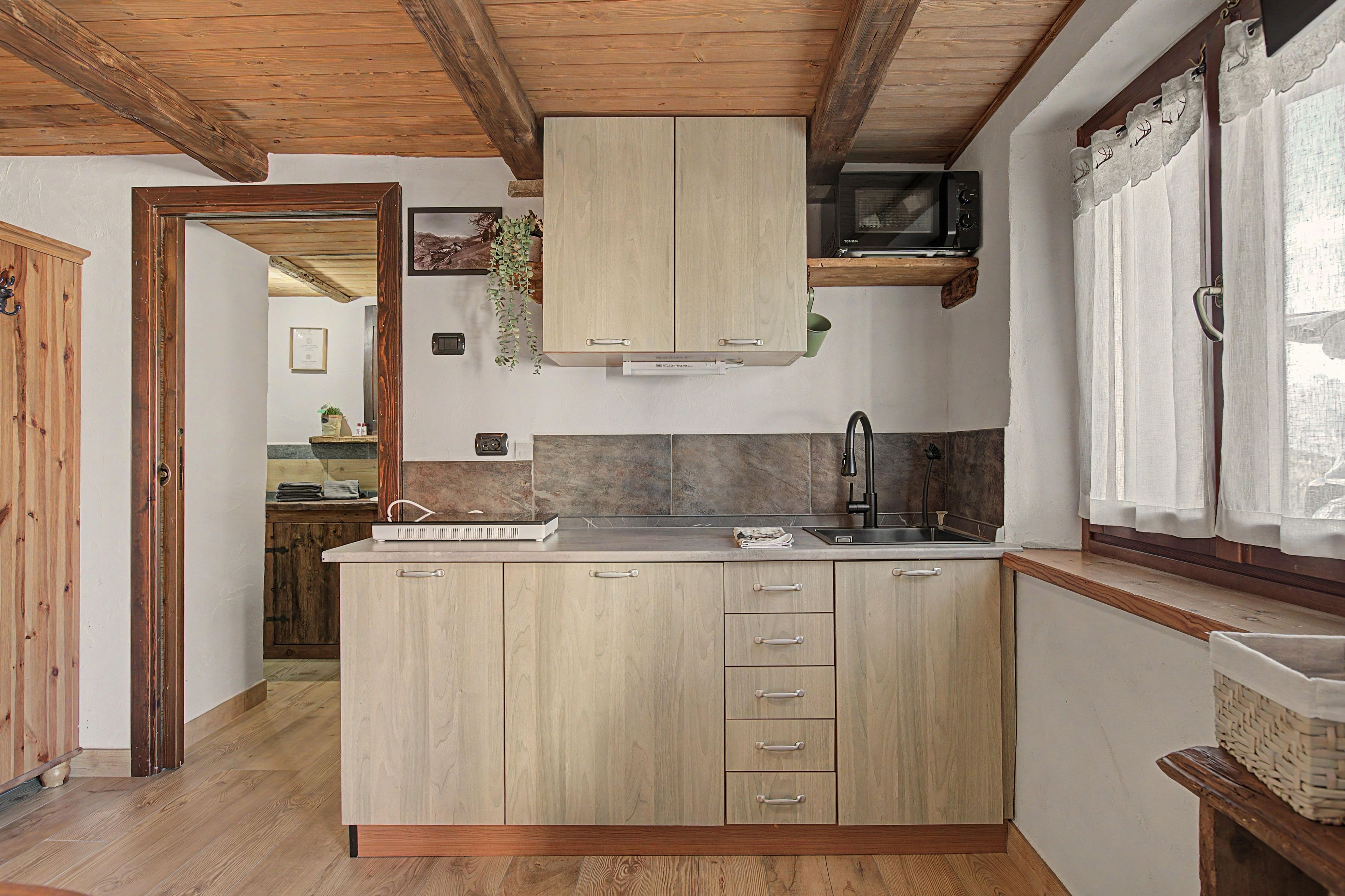 A kitchen with wooden cabinets, a microwave, and a sink.